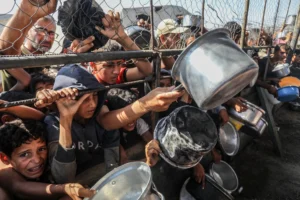 Palestyńczycy czekają na ciepły posiłek rozdawany przez organizacje pomocowe w rejonie al-Mawasi w Khan Yunis, Gaza [Foto: Abed Rahim Khatib/Anadolu]